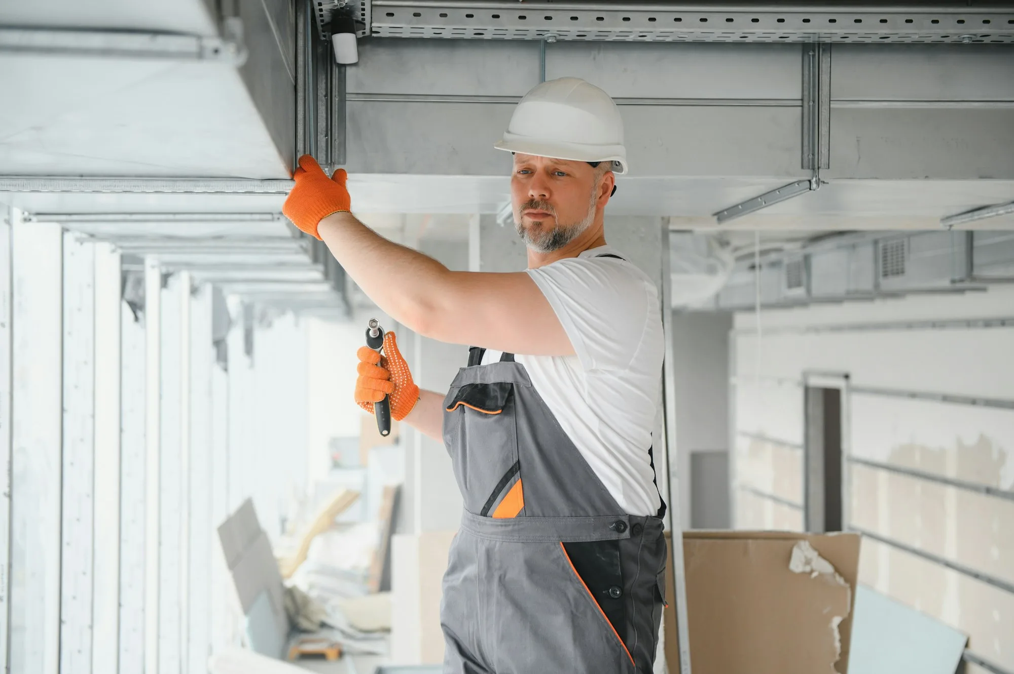 Technician installing ducted ventilation overhead as part of a home efficiency upgrade