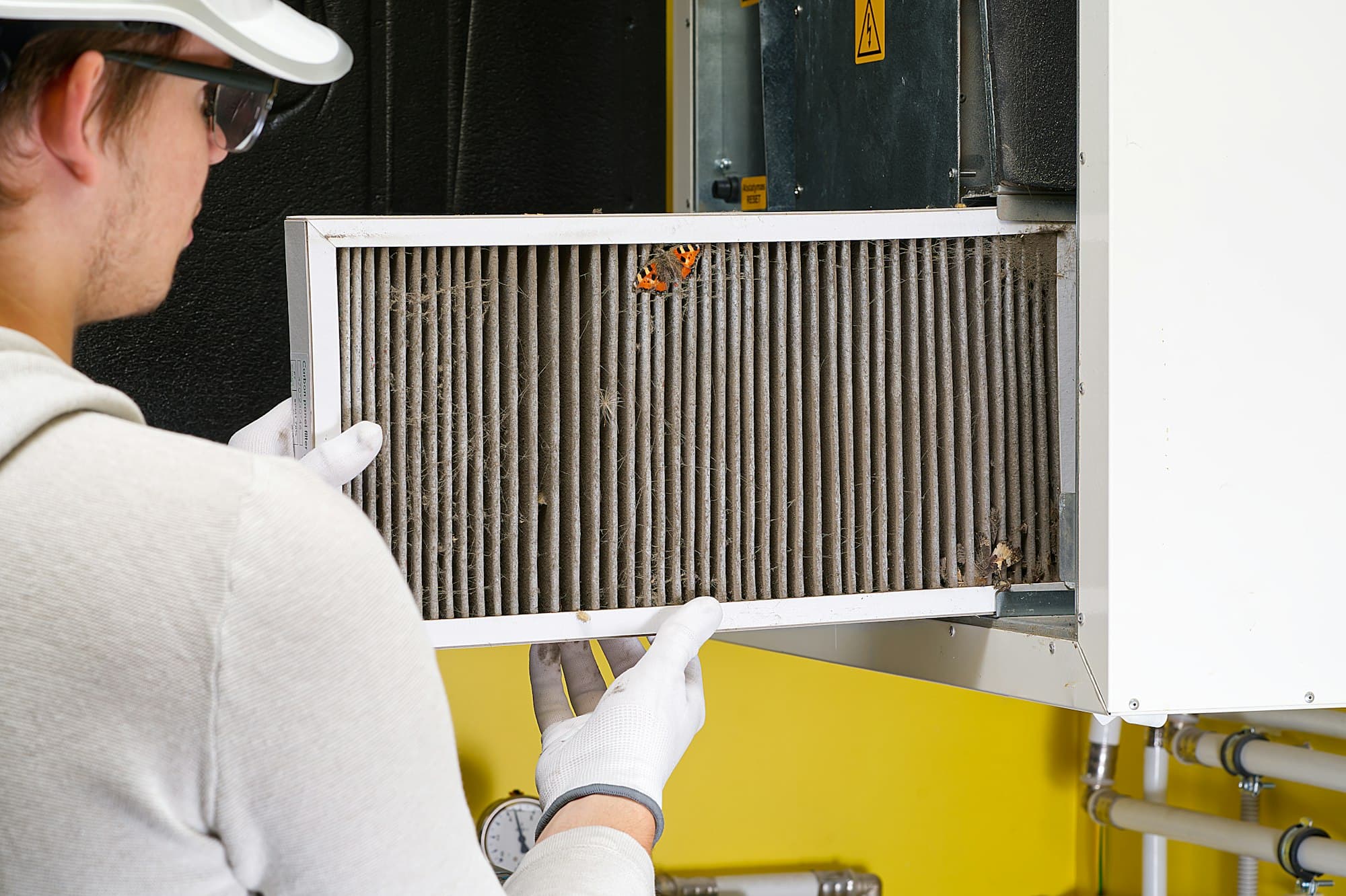 Technician removing a heavily lint-clogged filter from a home ventilation system